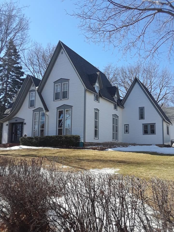 Gothic-revival exterior finished in white, gray-trimmed windows under steep gables.