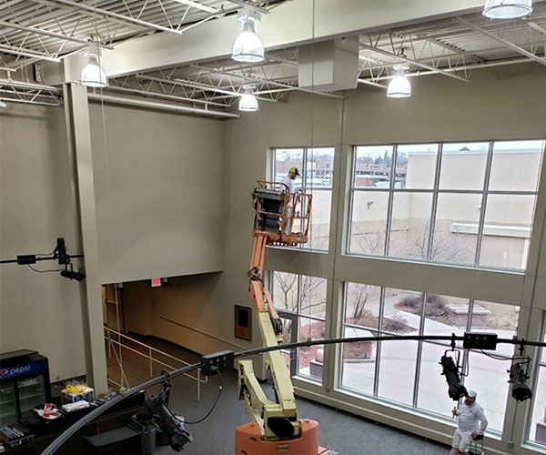 Lift work along the glass wall of a large commercial interior.