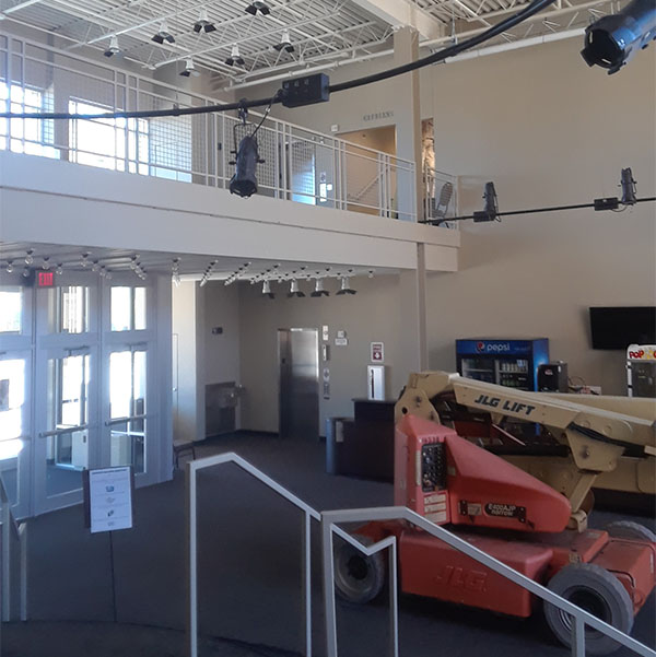 A boom lift staged under the mezzanine of a commercial venue.